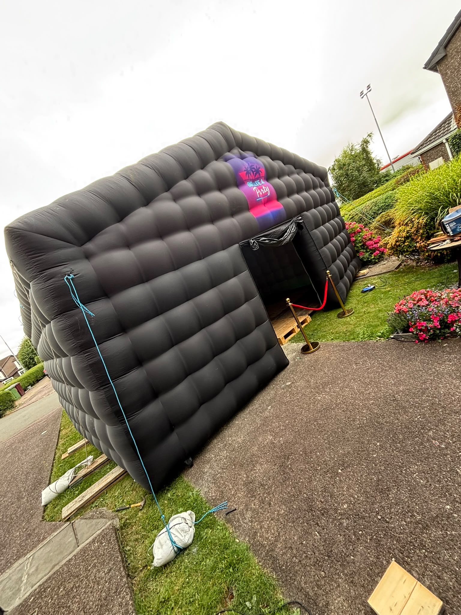 Inflate A Party branded nightclub tent with red velvet ropes and gold stanchions